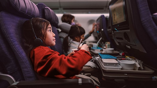 Girl on plane entertained by in-flight system