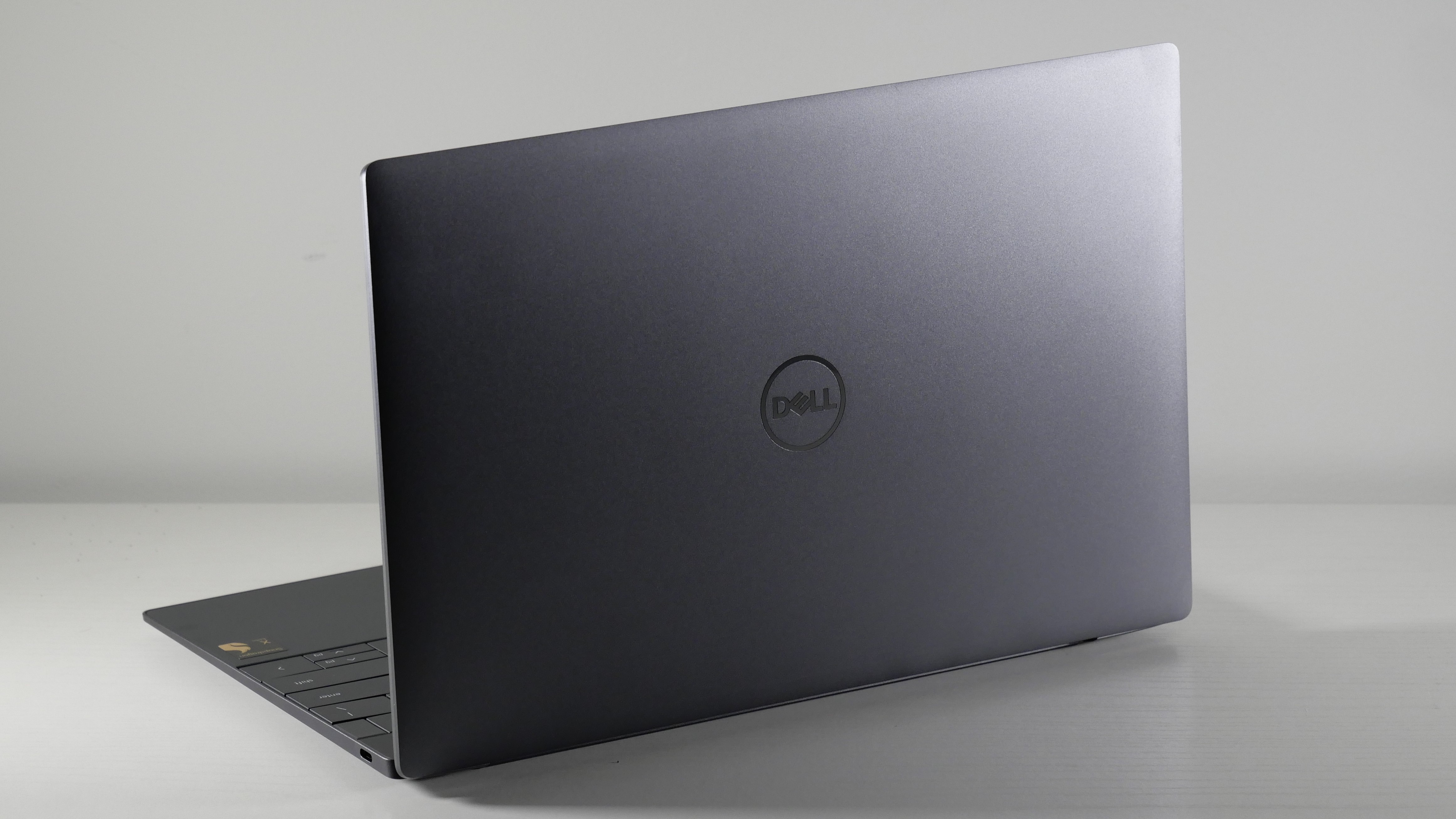 Dell XPS 13 9345 (Snapdragon X Elite) open on a white desk angled away from camera showing the lid.
